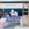 Oak and white bunk bed face on to camera, with an Indigo blue wall and girls bedding on the bed.