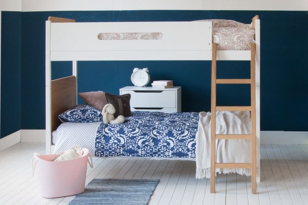 Oak and white bunk bed face on to camera, with an Indigo blue wall and girls bedding on the bed.