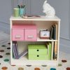 small white bookcase with two shelves, filled with books, boxes and stationery.