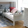 Close up of a child's day bed in light grey with a shelf on the end of the day bed.