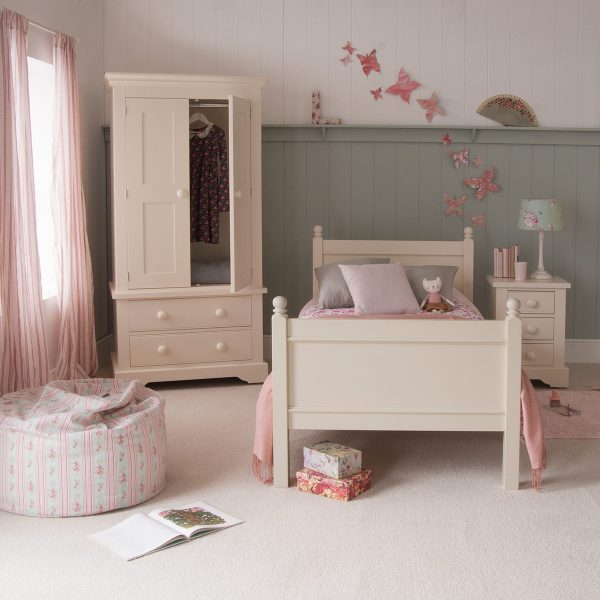Cream kids single bed and wardrobe with open door in girls bedroom with butterflies on wall