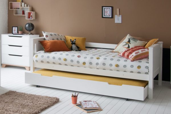 Day bed with trundle pulled out as a sleepover bed, next to a chest of drawers against a tan wall